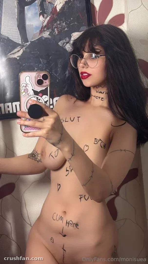 Monii♡ tira uma selfie de espelho com texto escrito à mão no corpo, usando óculos e batom vermelho.