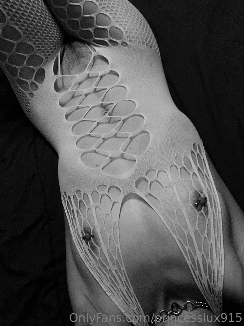 Gros plan en noir et blanc de Princess Lux portant un bodystocking à motifs sur un fond sombre