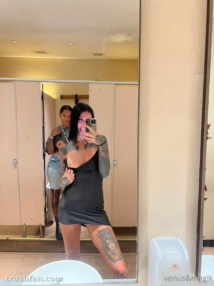Creator in a black dress taking a mirror selfie with another creator in denim behind her.