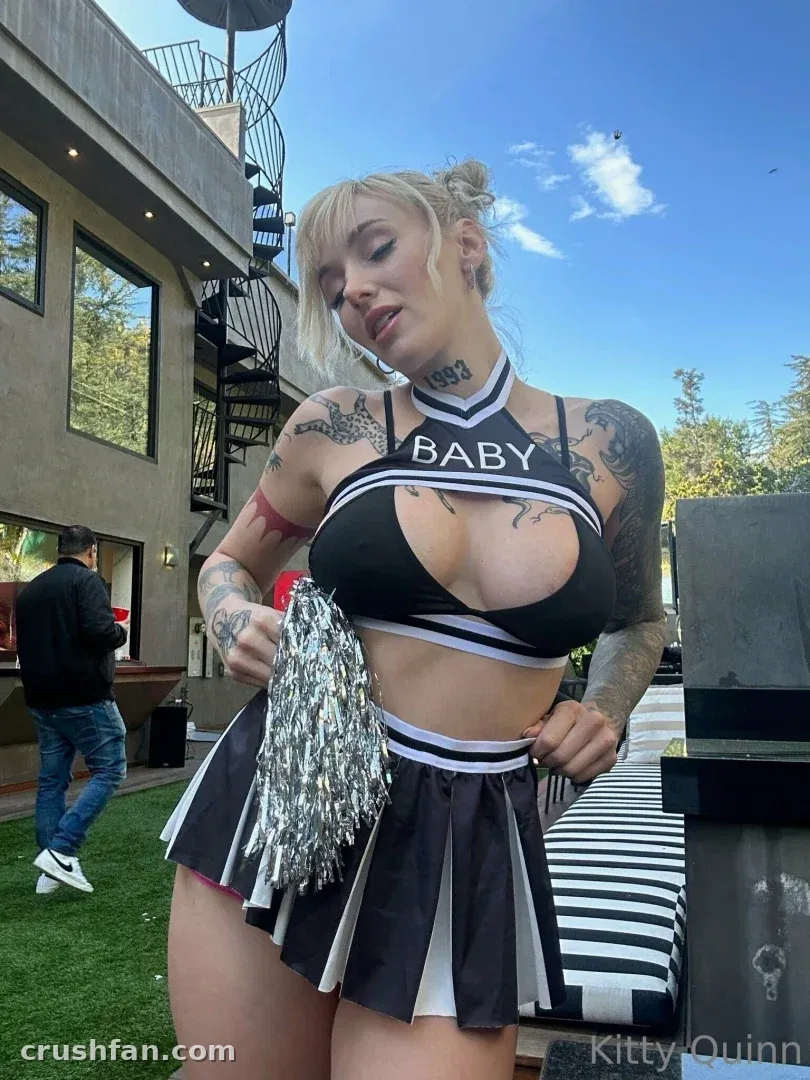 Creator in einem schwarz-weißen Cheer-Outfit, der im Freien einen silbernen Pom-Pom hält.