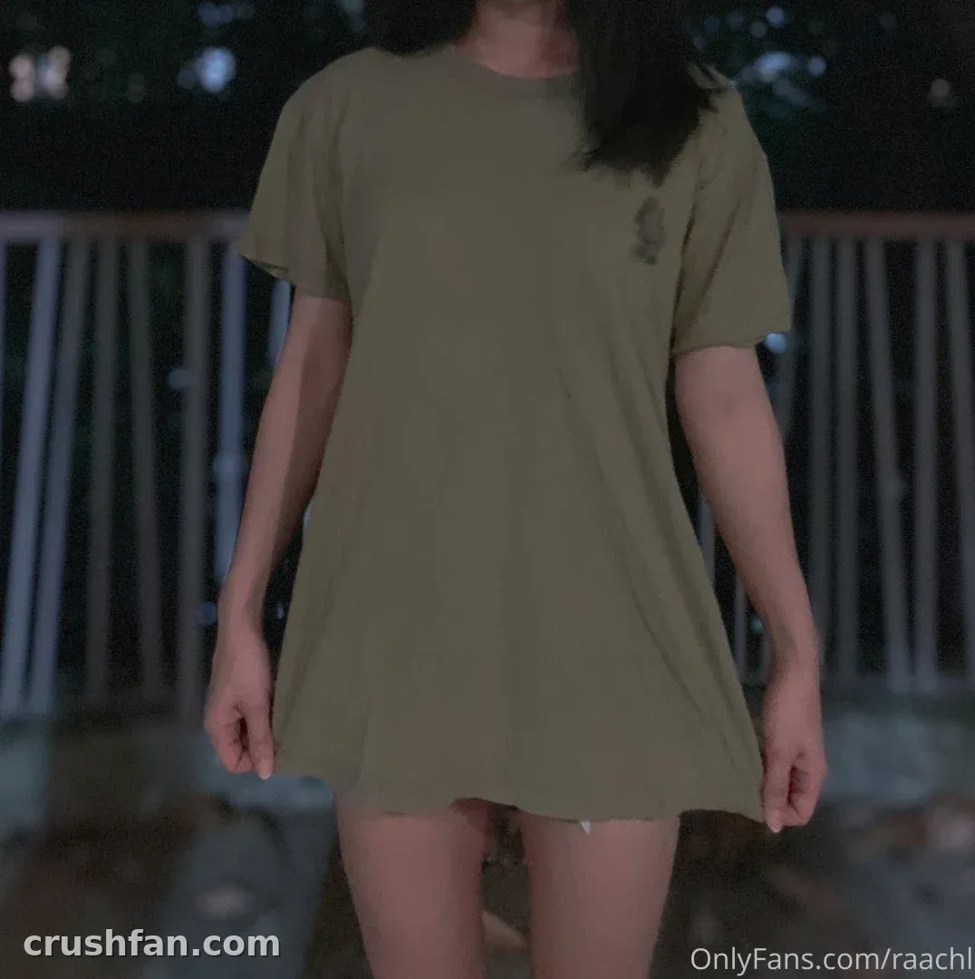 Rachel in an oversized olive t-shirt standing outdoors at night
