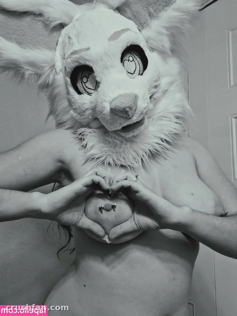 Marie Anarchy wearing a furry rabbit mask and making a heart shape with her hands in a black and white photo.