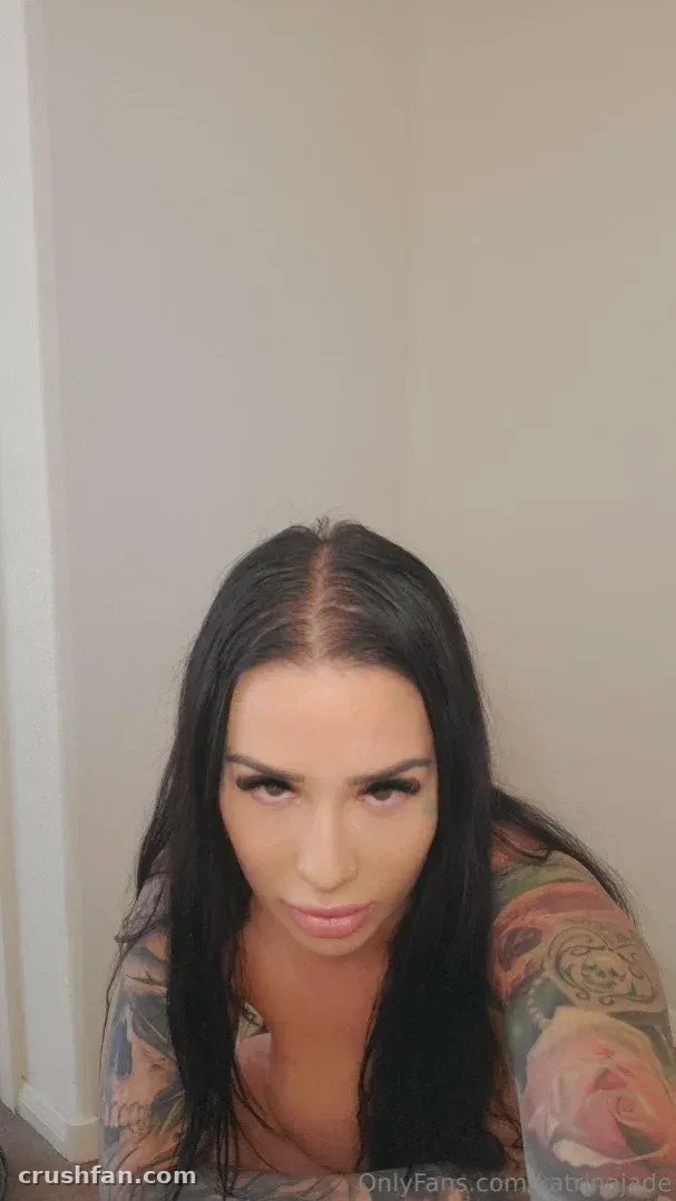 Katrina Jade with long dark hair and floral arm tattoos indoors