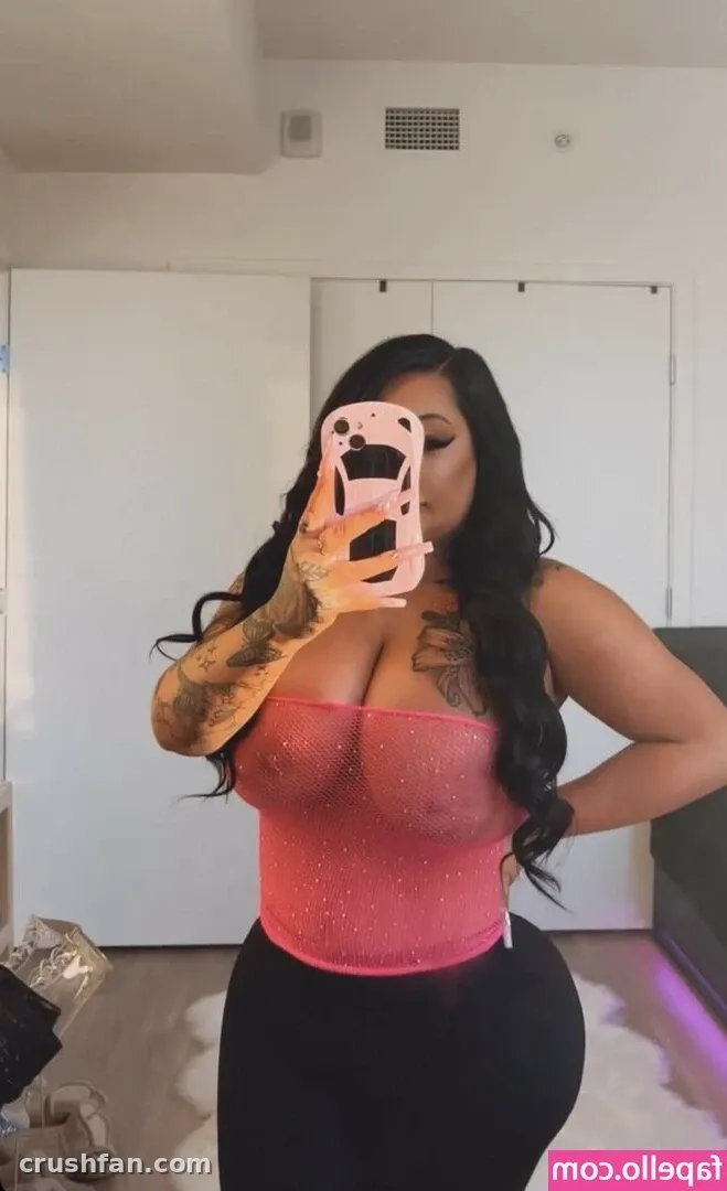 Brandi Bae taking a mirror selfie in a pink sparkly top and black leggings indoors.