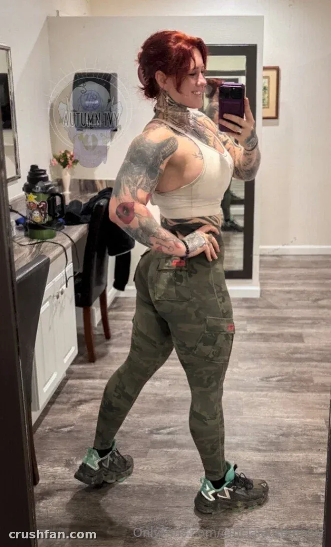 Autumn Ivy takes a mirror selfie in a white crop top and camouflage trousers.