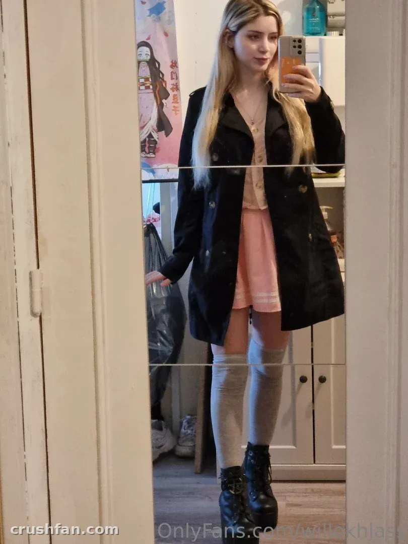 Willokhlass taking a mirror selfie in a black coat and pink skirt
