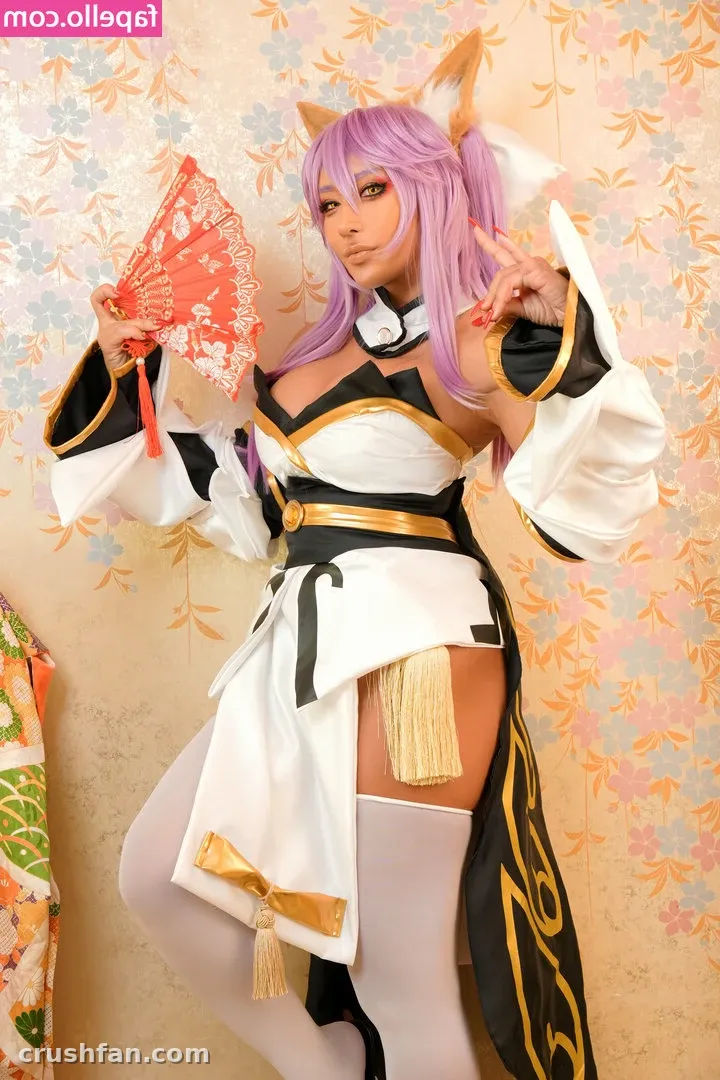 Cosplayer in purple wig and white costume holding a red fan against floral wallpaper