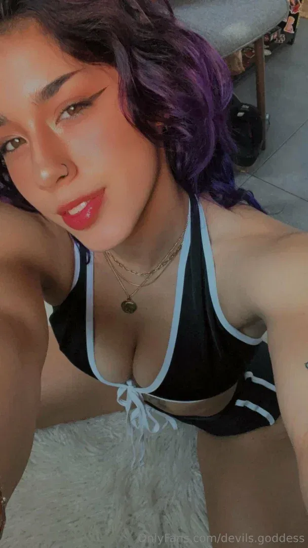 Tovi tirando uma selfie de perto com um top frente única preto e branco e cabelo roxo.