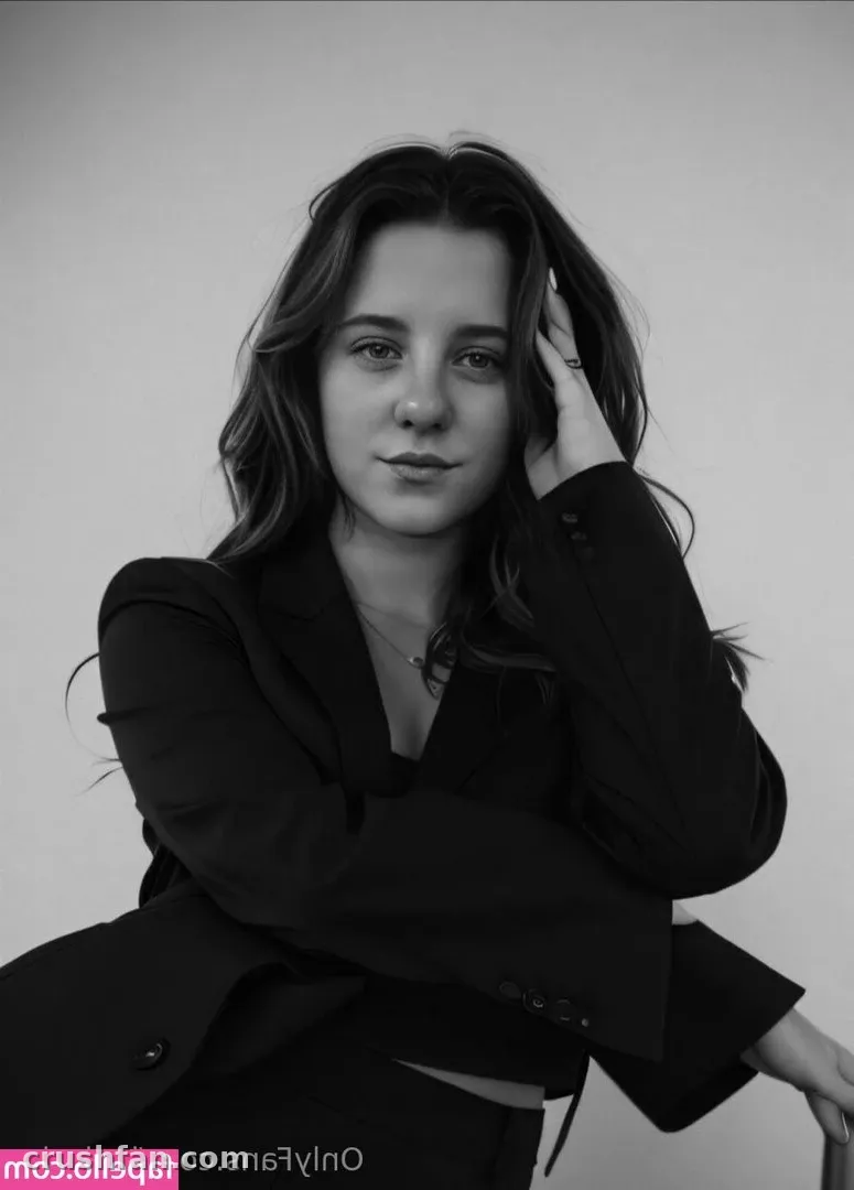 Retrato de estúdio em preto e branco de Leyla com um blazer escuro e uma mão perto do cabelo