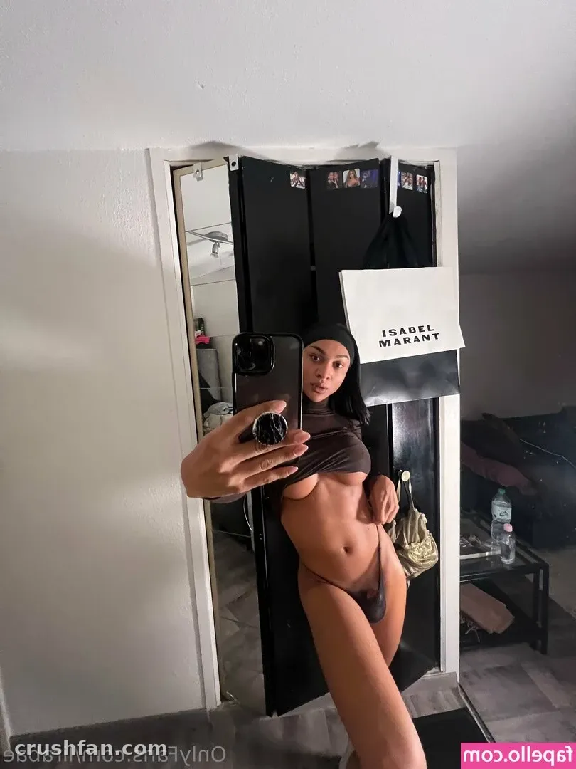Creator in a brown two-piece set taking a mirror selfie in a doorway with a shopping bag nearby