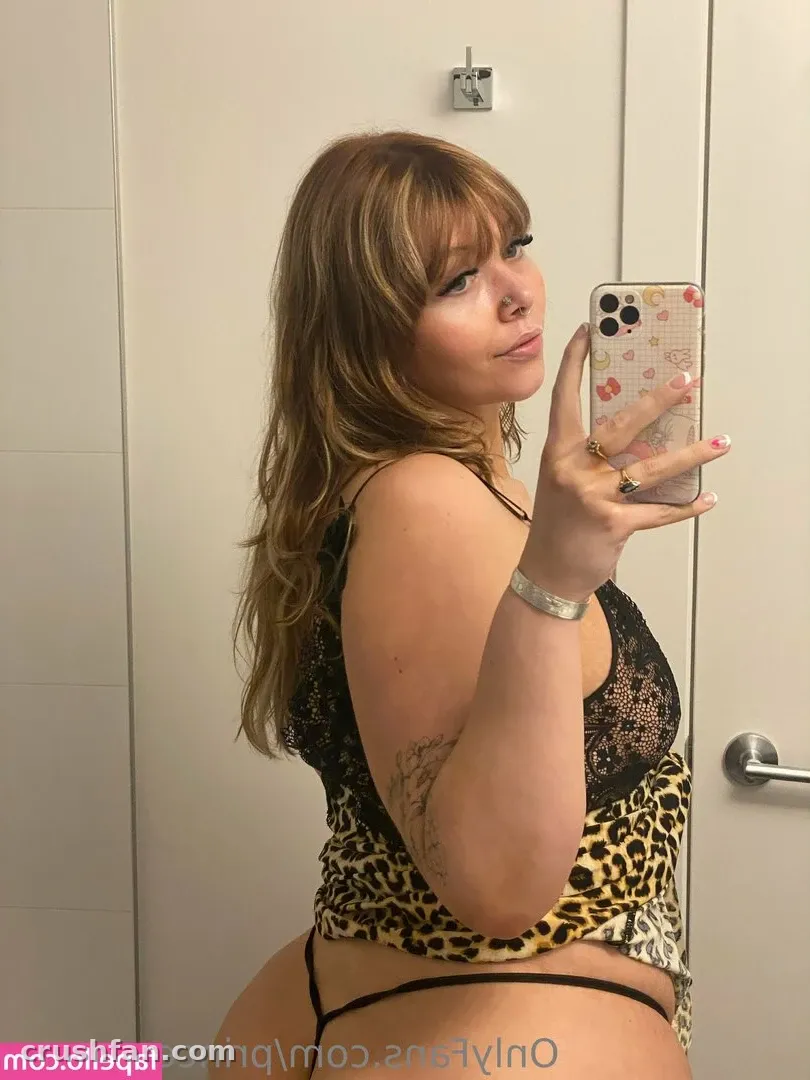 Creator in a leopard and black lace top taking a mirror selfie in a bright bathroom