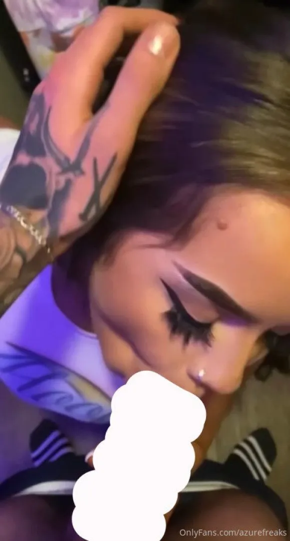 Close de Azure com uma mão tatuada em seu cabelo sob luz roxa