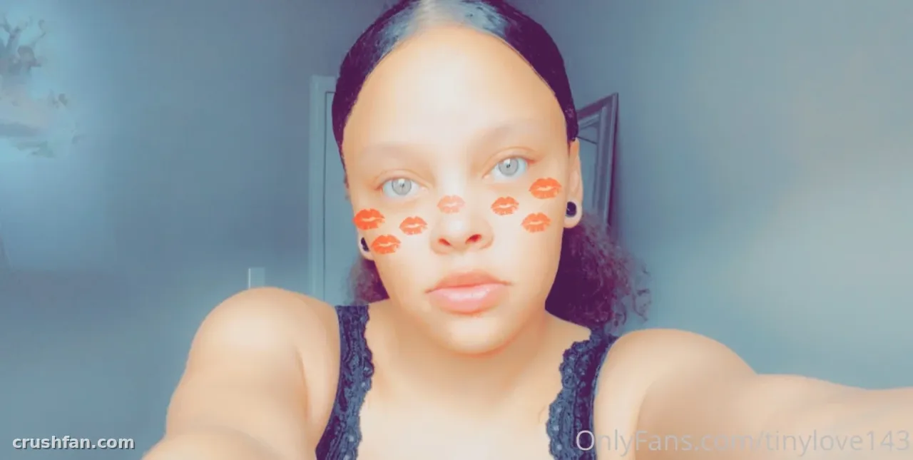 La creadora Tinylove143 se toma una selfie en primer plano en interiores con marcas naranjas de labios en la cara.