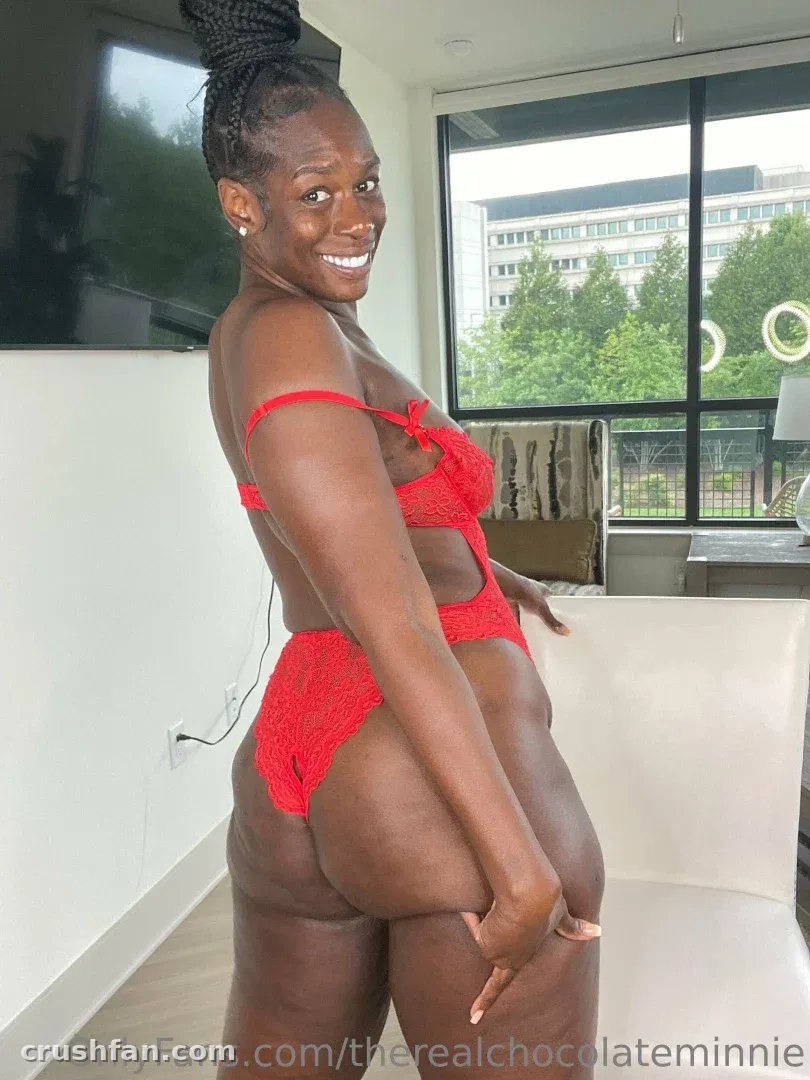 Jasmine en lingerie en dentelle rouge souriant près d'une fenêtre