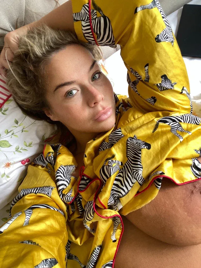 E CUP ERIN in a yellow zebra print robe lying on a bed with a floral pillow.