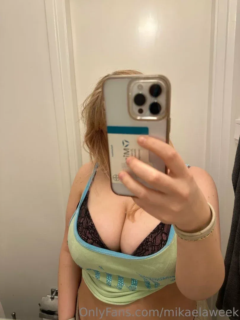 Mika22 prenant un selfie dans le miroir avec un crop top vert menthe et un bralette en dentelle.