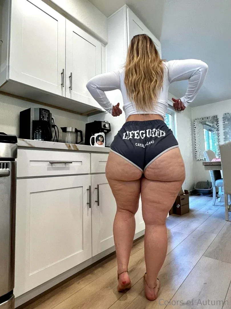 Autumn com um top branco e shorts escuros em pé em uma cozinha iluminada
