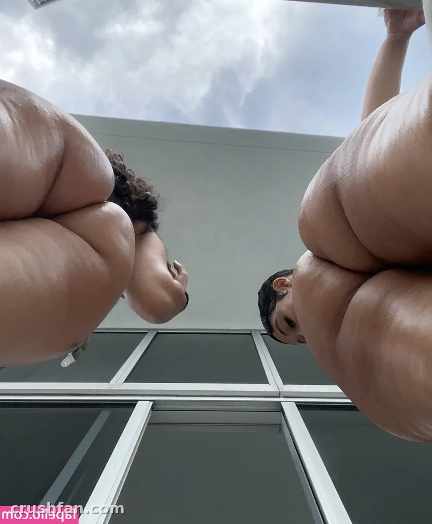 AmberThickk fotografiada desde abajo al aire libre frente a un edificio claro y un cielo nublado
