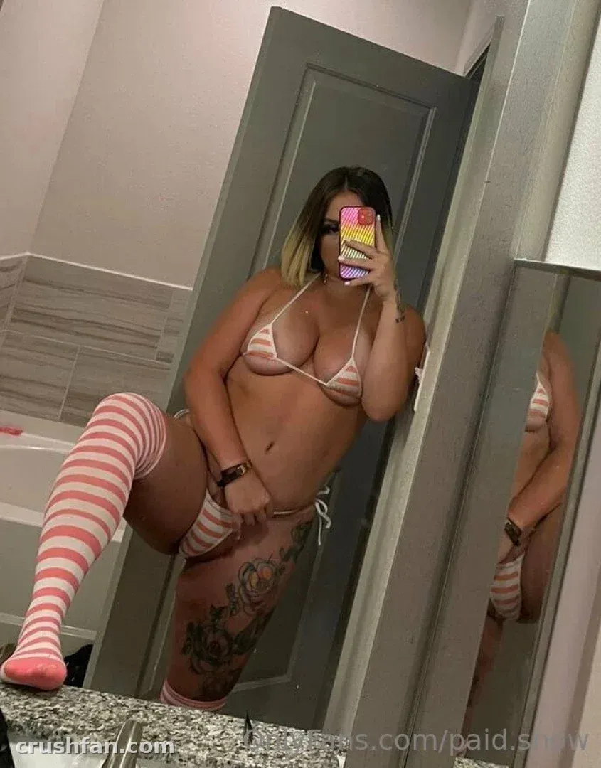 Snow taking a mirror selfie in a bikini and striped thigh-high socks.