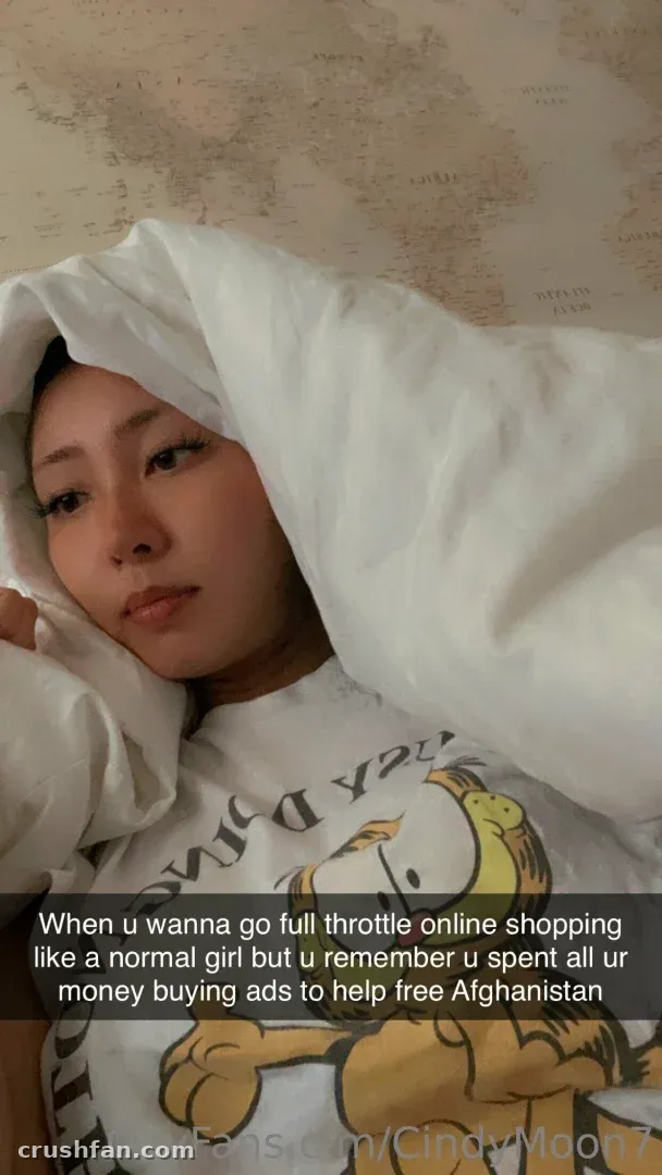 Cindy Moon enveloppée dans une couette blanche portant un haut graphique en intérieur