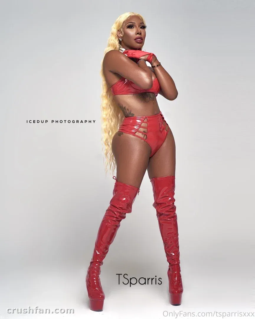 Criadora com um conjunto de duas peças vermelho brilhante e botas vermelhas até a coxa posando em um estúdio