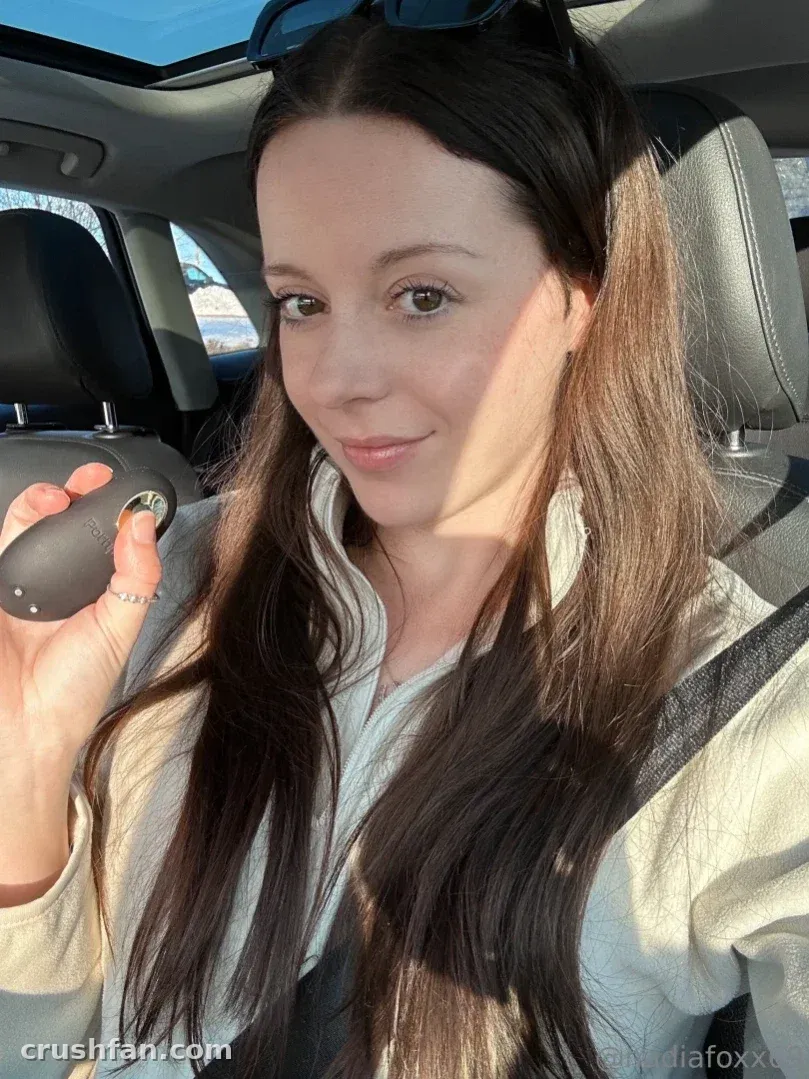 Nadia Foxx smiling in a car with sunglasses on her head and sunlight through the window.