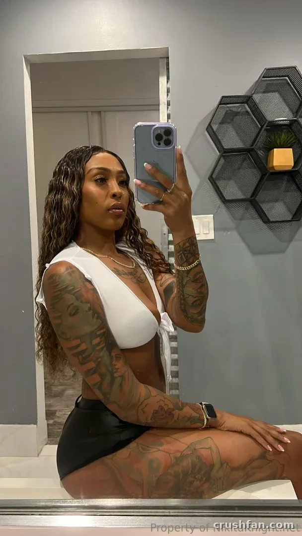 NikitaKnight prenant un selfie dans le miroir avec un haut blanc et un bas noir