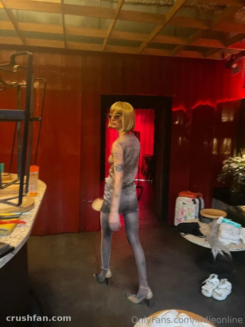 Indie Puesta con pintura corporal plateada de pie en una sala de estudio con luz roja