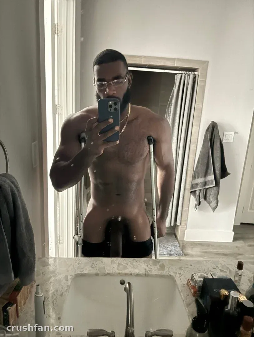 Marshall Price tirando uma selfie no espelho em um banheiro enquanto usa muletas.