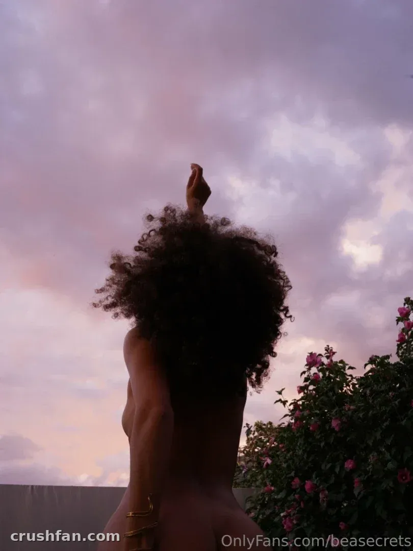 Beatrice Segreti with an arm raised against a pastel sunset sky.
