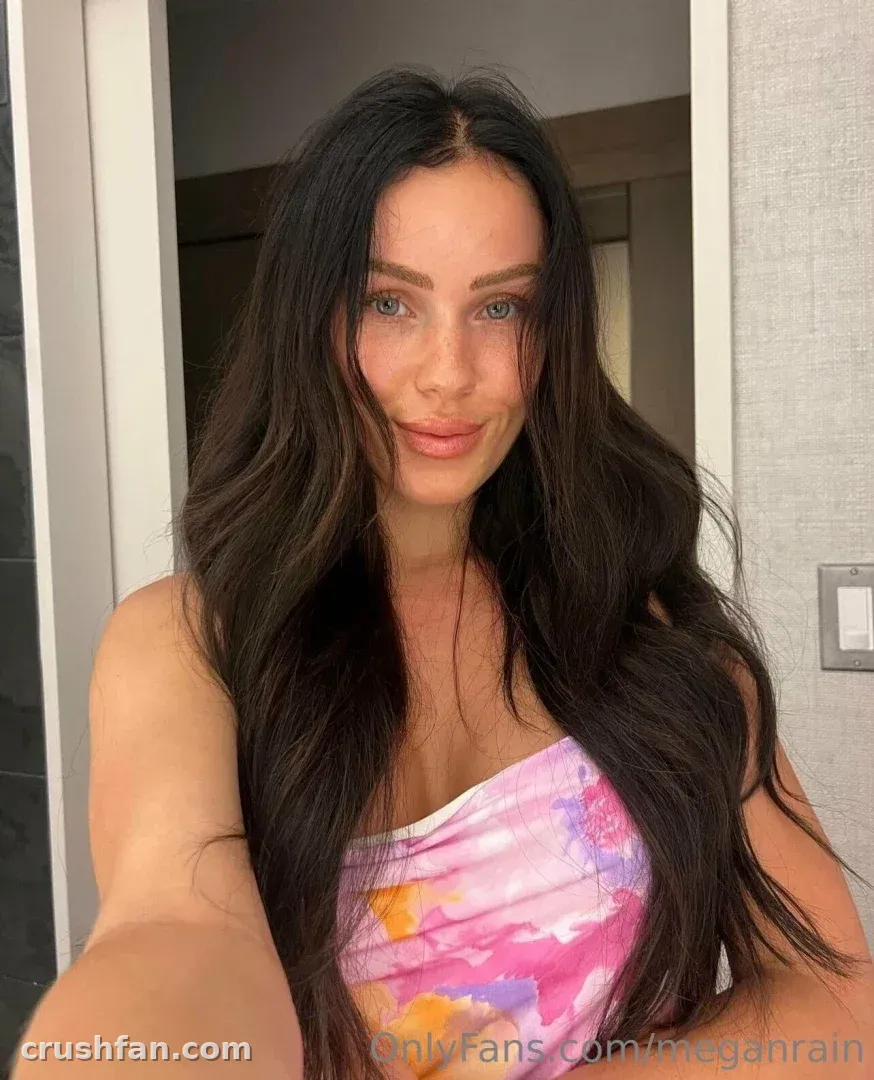 Megan Rain taking a close indoor selfie in a pink watercolour strapless top