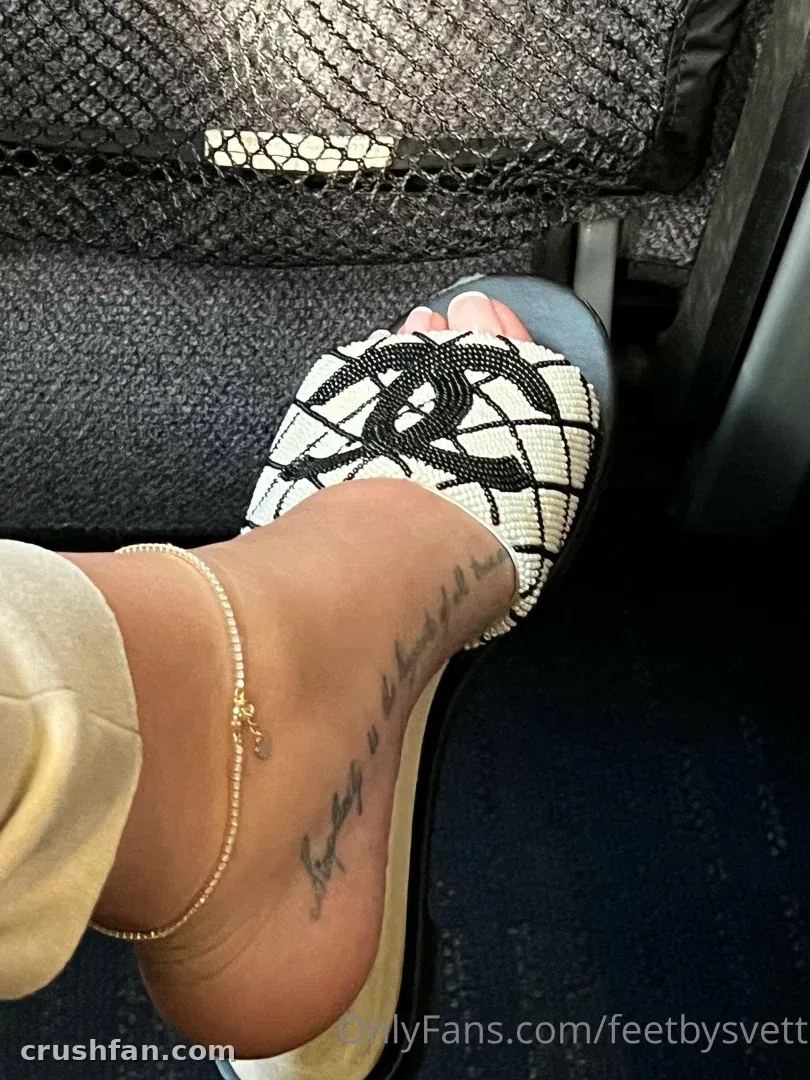Primer plano de un pie con una sandalia de cuadros en blanco y negro, tobillera dorada y tatuaje en cursiva.
