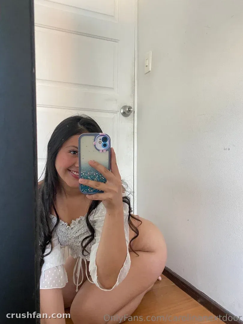 Carolina prenant un selfie dans le miroir avec un haut blanc en dentelle à l'intérieur.