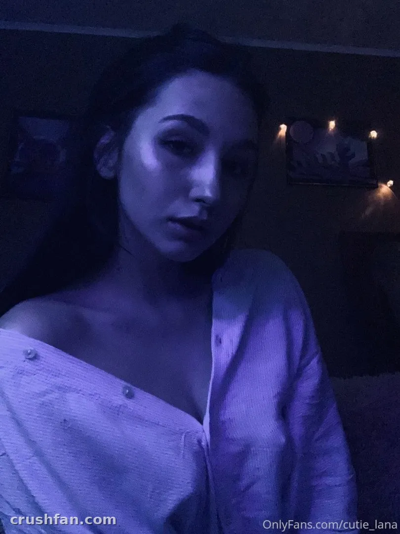 Cutie Lana in einem blau beleuchteten Raum mit einem Off-Shoulder-Hemd