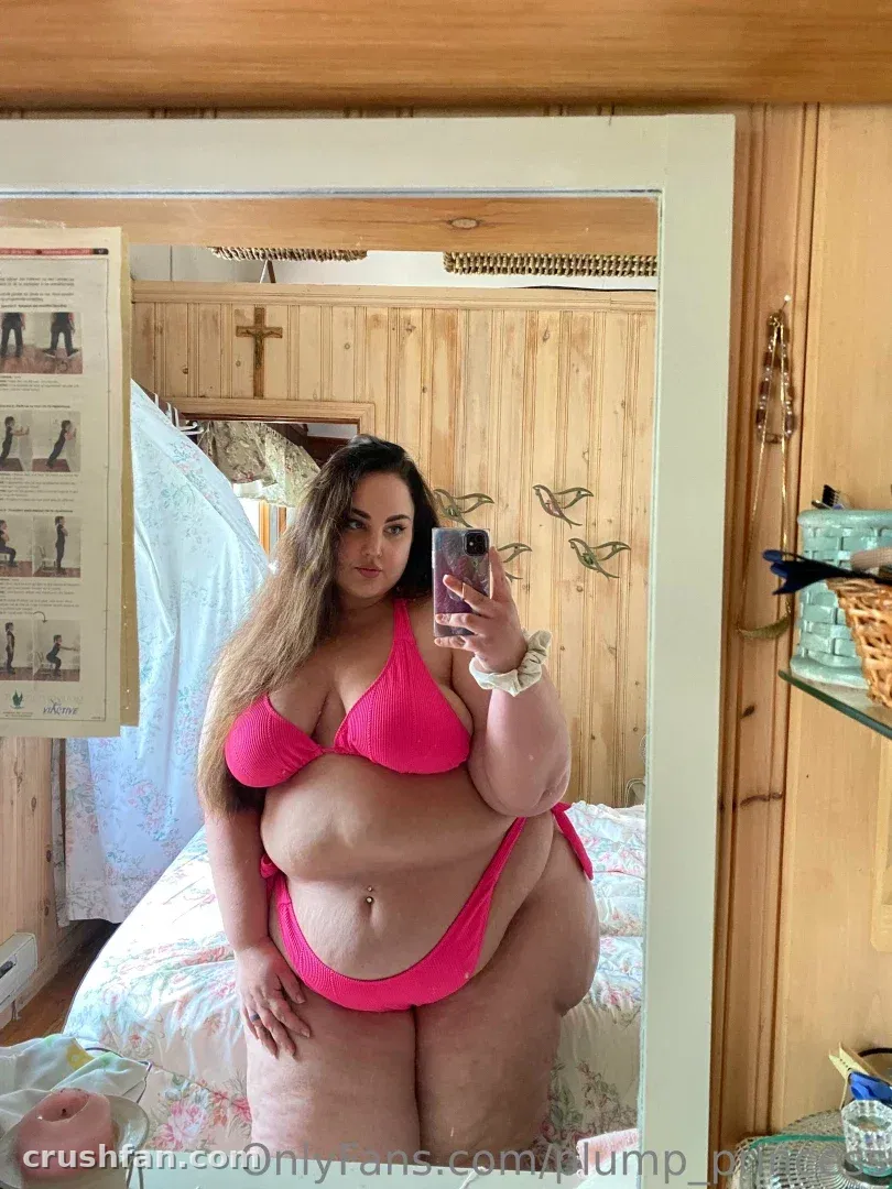 Creadora con un conjunto de dos piezas rosa tomándose una selfie frente al espejo en una habitación con paneles de madera