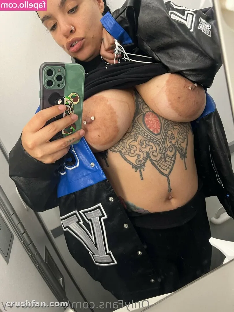 Creator in a black and blue varsity jacket taking a mirror selfie with a green phone case.