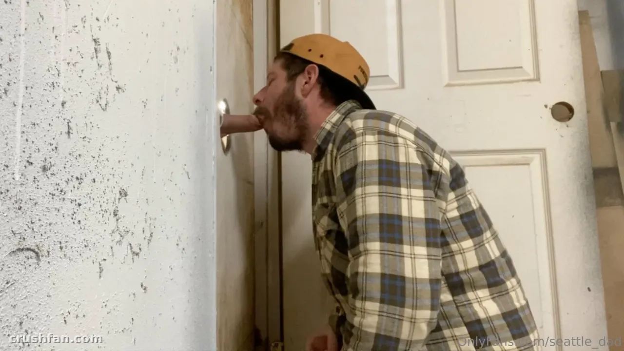 Seattle Dad in a plaid shirt and tan cap leaning toward a white door