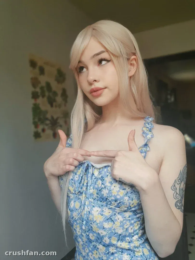 Gwen dans un haut floral bleu posant à l'intérieur avec un mur neutre derrière elle