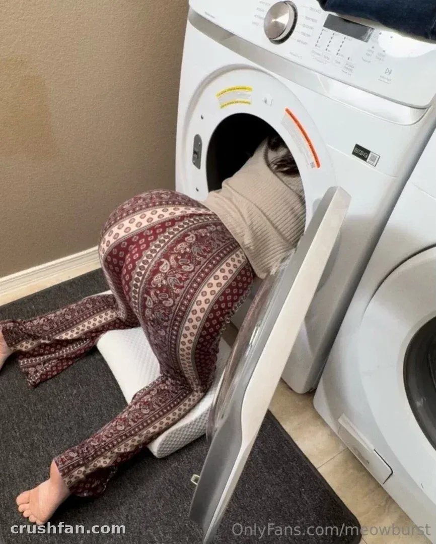 Creator in patterned trousers leaning into an open washing machine in a laundry room