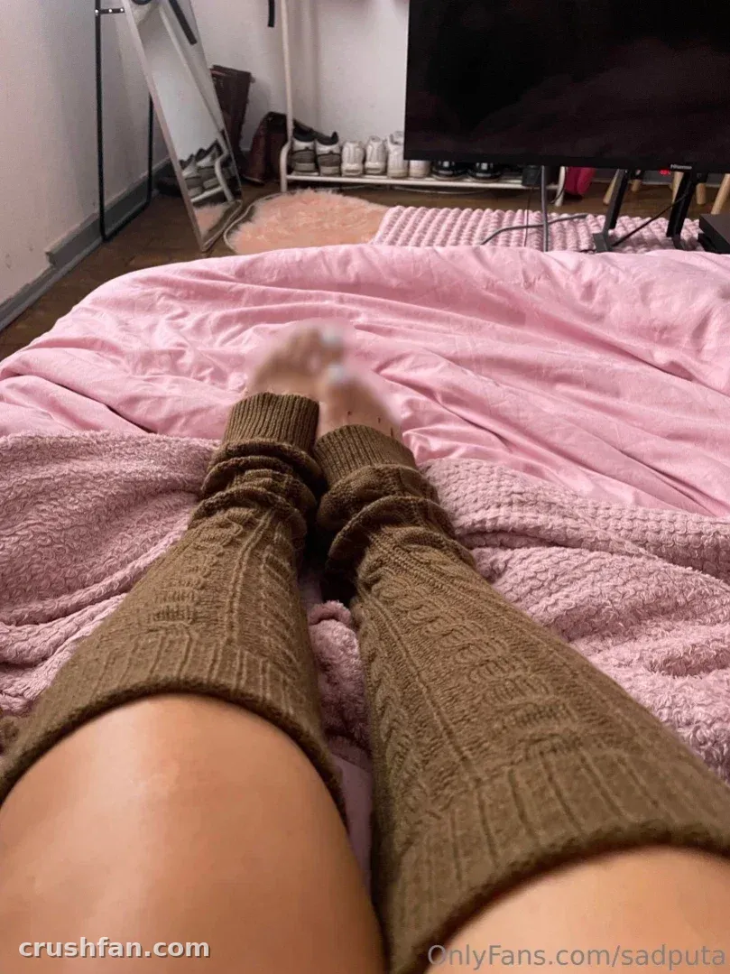 Creator entspannt auf einem rosa Bett und trägt braune Strick-Stulpen.