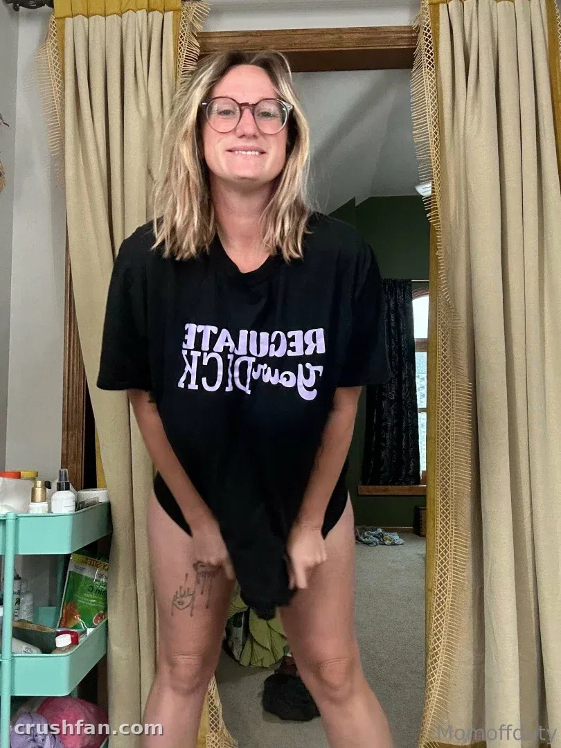 Momoffduty in an oversized black tee standing in a curtained doorway indoors