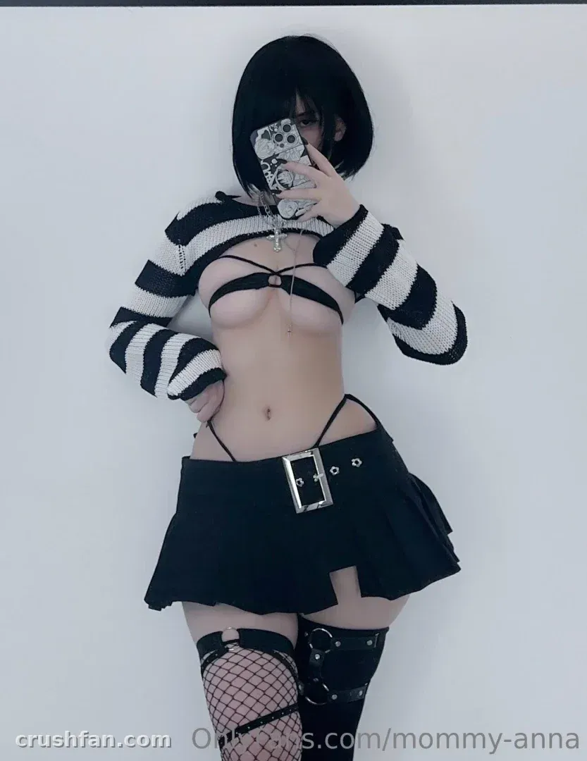 Anna en pull court rayé et mini-jupe noire prenant un selfie miroir devant un mur blanc