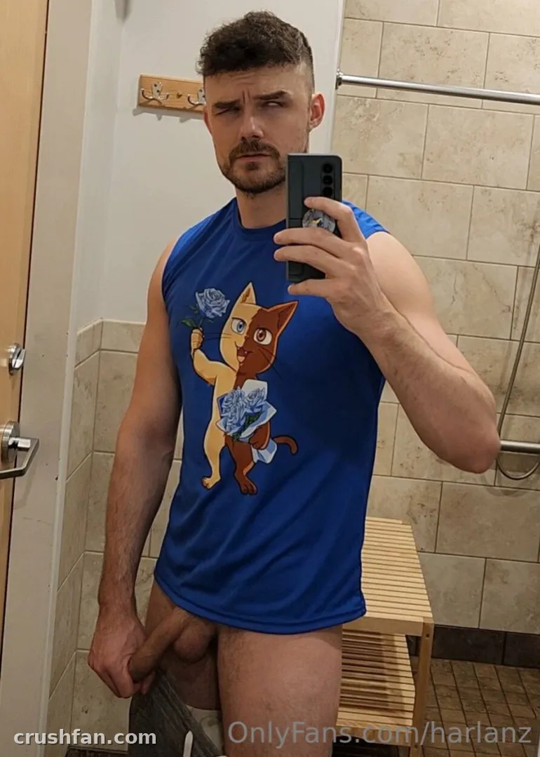 Créateur en débardeur bleu imprimé d'un chat prenant un selfie dans le miroir de la salle de bain
