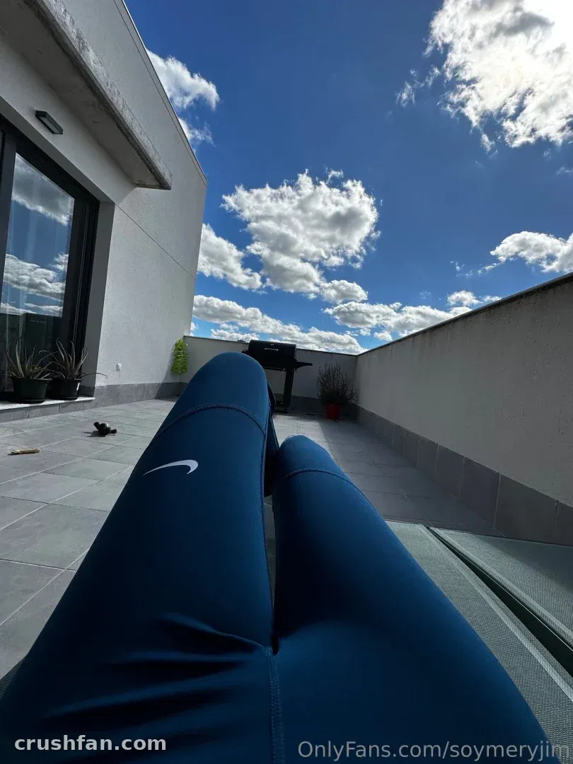 Dunkelblaue Sporthose, getragen von einer Frau, die auf einer Dachterrasse unter einem bewölkten blauen Himmel entspannt.
