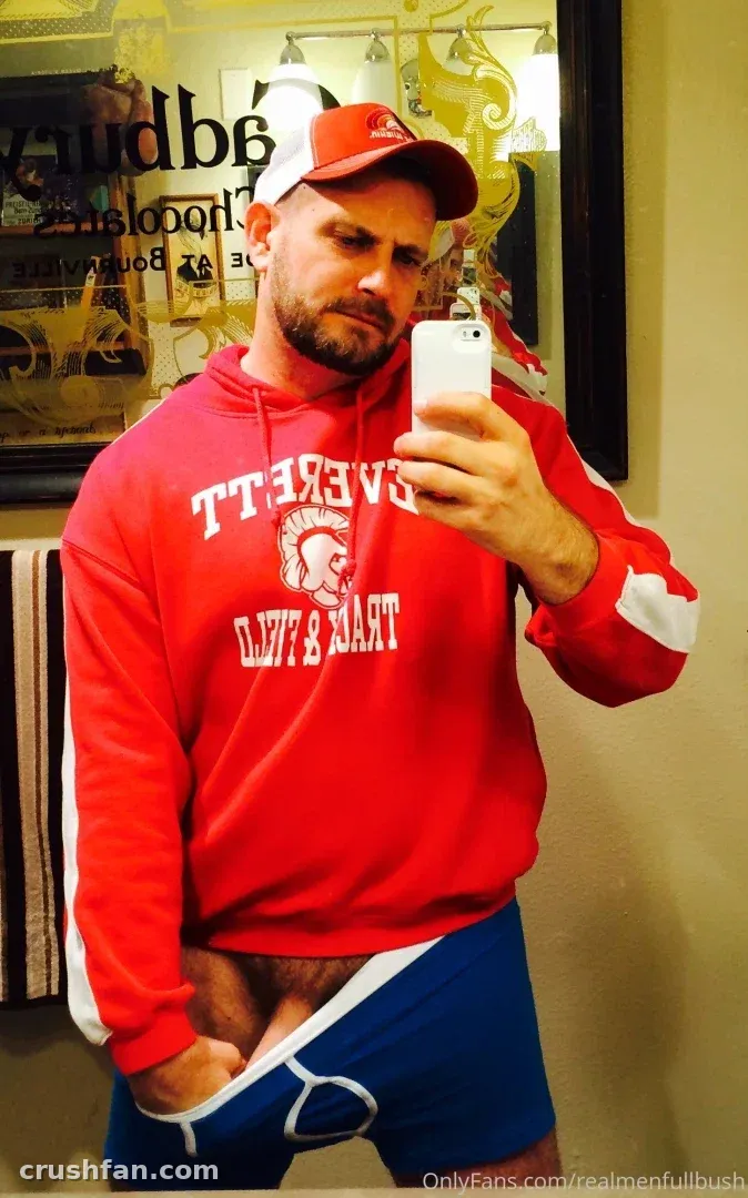 Seattle Dad in einem roten Hoodie und blauen Shorts macht drinnen ein Spiegel-Selfie.