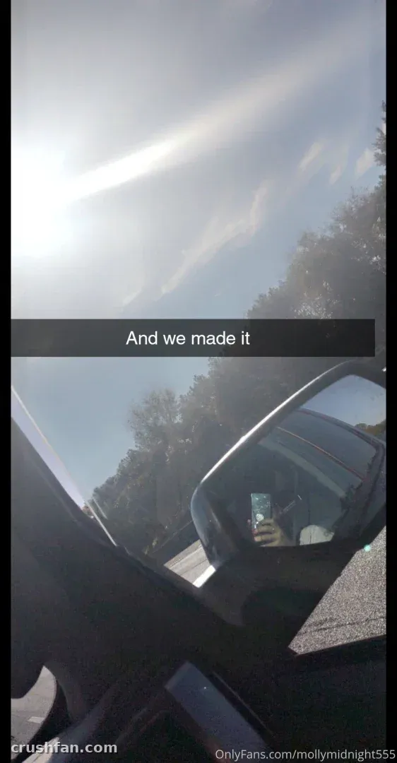 View from inside a car showing bright sky, a caption and a side mirror reflection