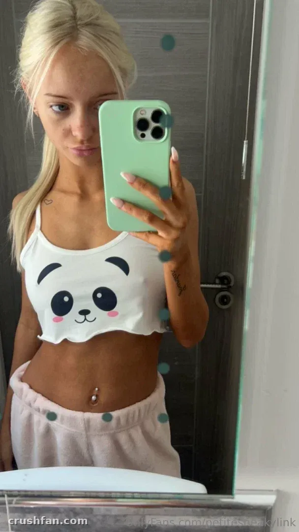 PetiteSneakyLink macht ein Spiegel-Selfie in einem Panda-Crop-Top und rosa Loungewear.