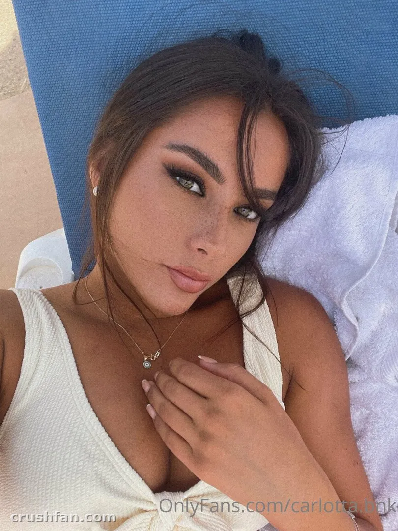 Carlotta in a white top lying on a blue lounger outdoors, looking at the camera