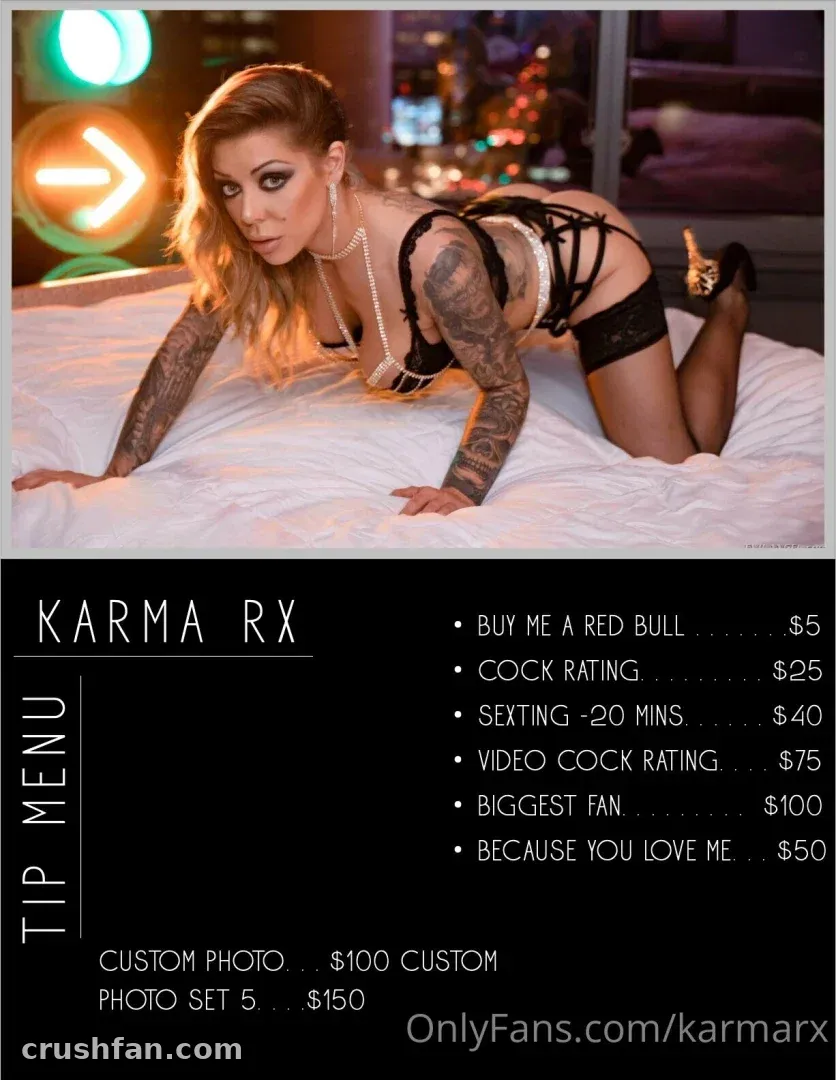 Karma Rx in black lingerie lying on white bedding with neon lights behind her