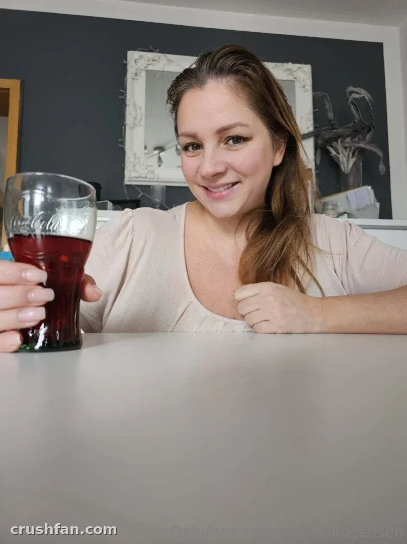Nadine Jansen souriant à une table avec un verre de soda foncé